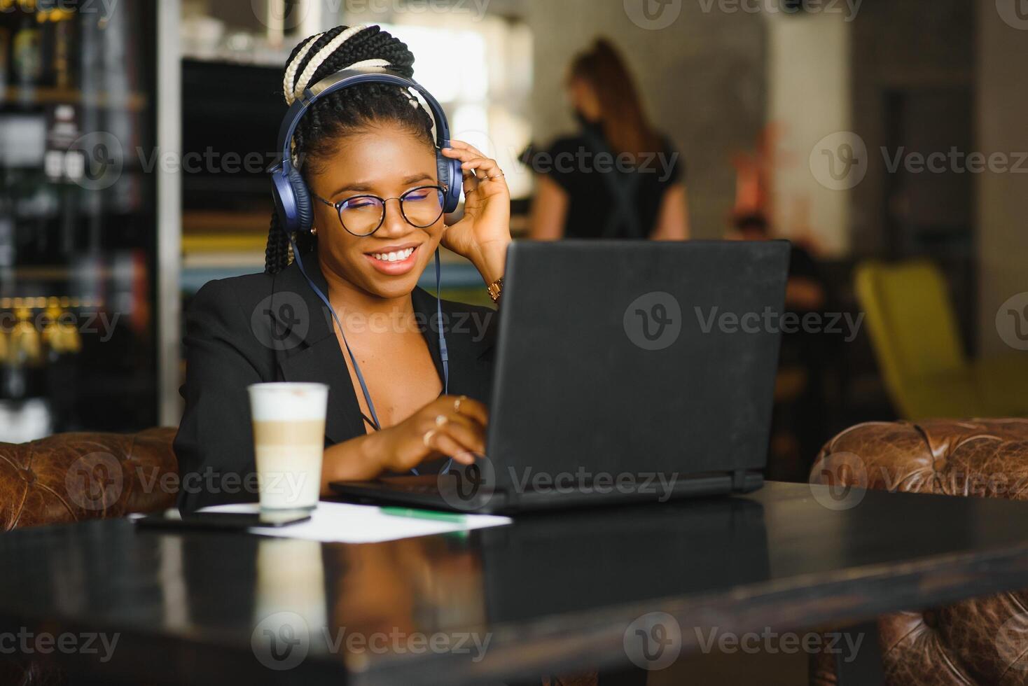 Attractive African American blogger with headphones and laptop communicating with followers in cafe photo