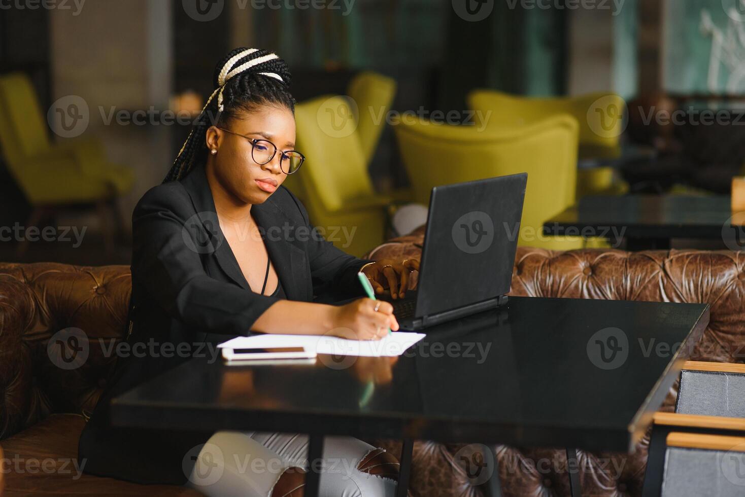 Focused female office worker using computer in coffee shop. African American business woman working on laptop in cafe and looking away. Internet technology concept photo