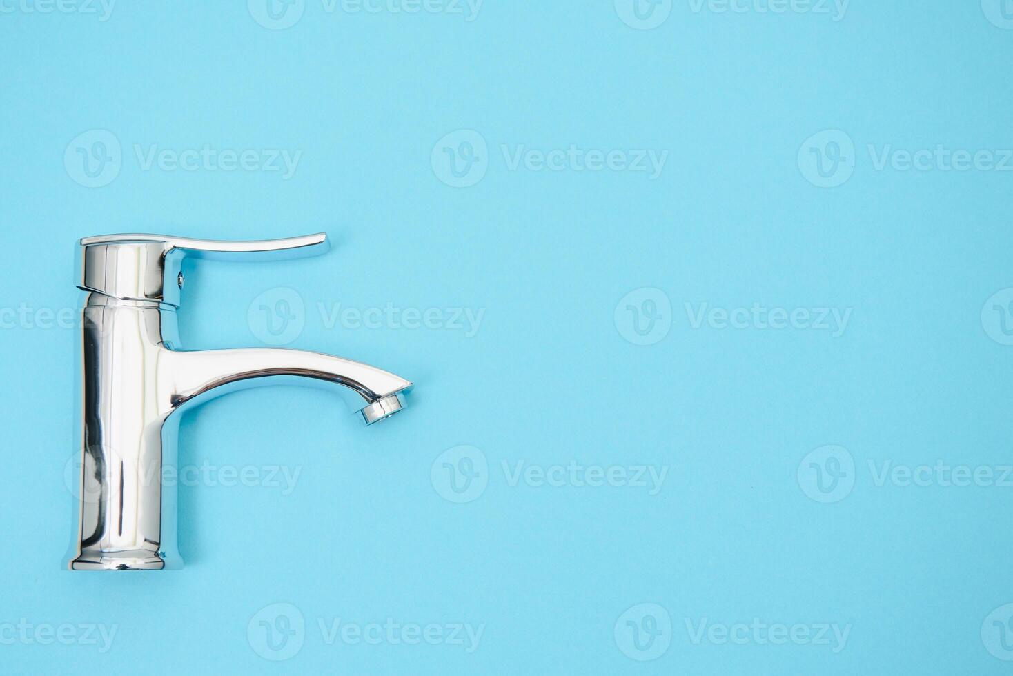 Single handle water tap on light blue background. New chrome or steel mixer tap . photo