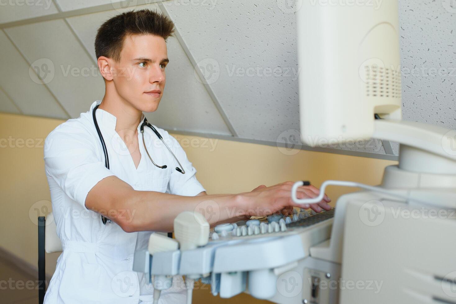 Portrait of young male technician operating ultrasound machine photo