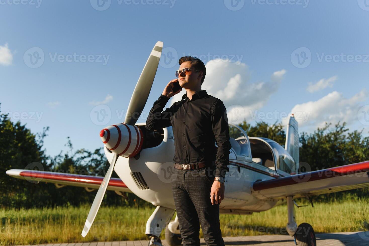 Business man with his airplanes. He is walking in the airport with the smart phone and making a call. photo