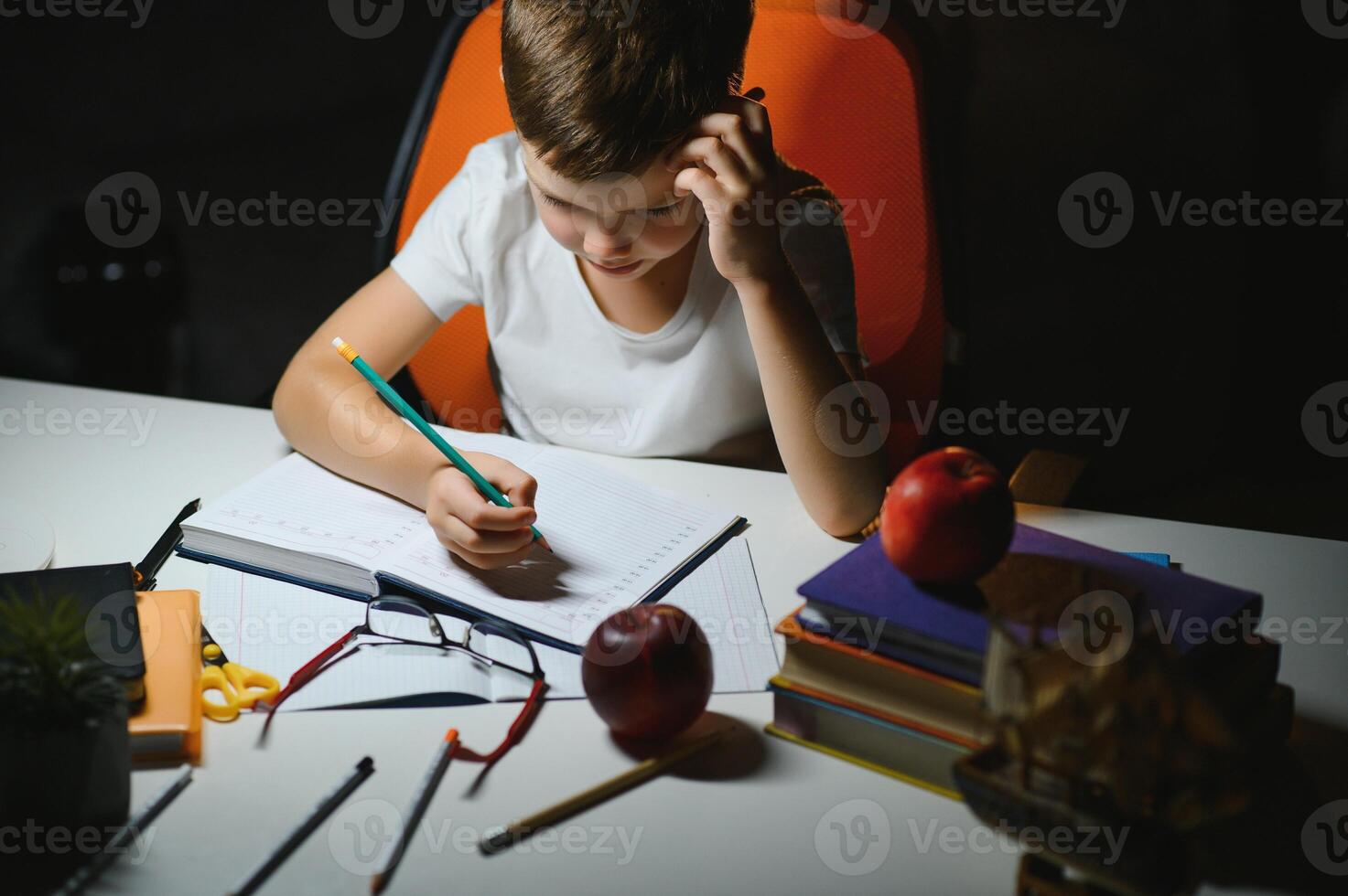 Boy learn lessons in the home setting at the table in the light of a table lamp. photo