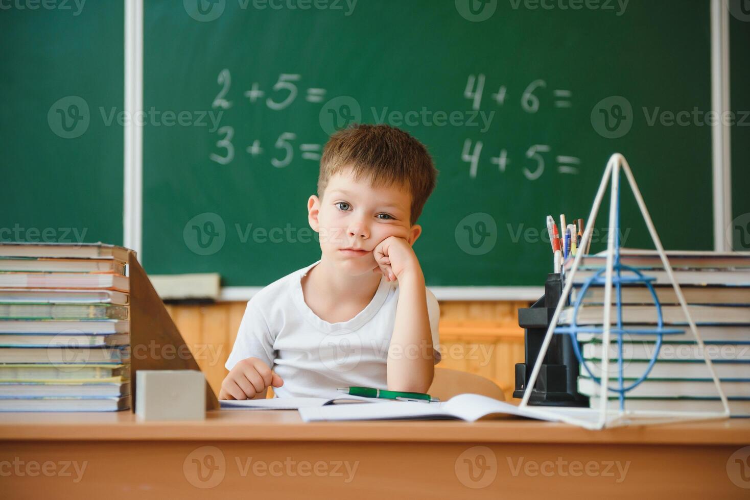 Back to school. Funny schoolboy sitting at a table with books in a school classroom. photo