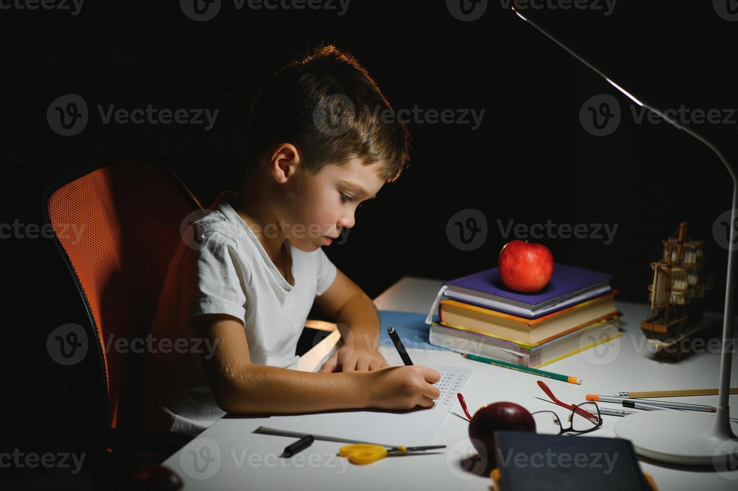 Boy learn lessons in the home setting at the table in the light of a table lamp. photo