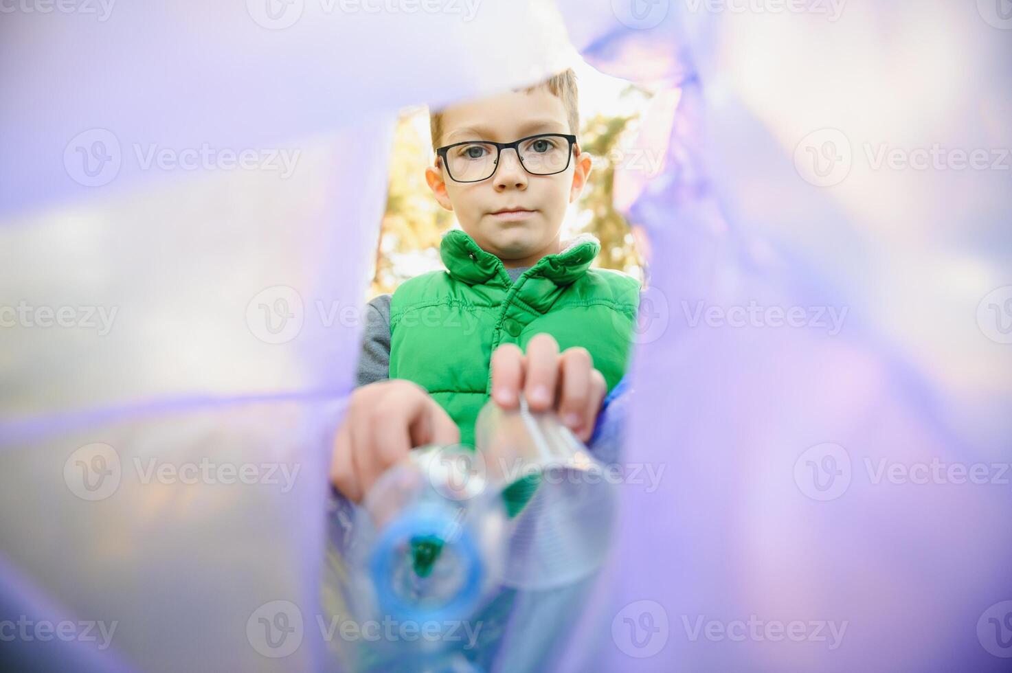 A seven-year-old boy at sunset is engaged in garbage collection in the park. Environmental care, recycling. photo