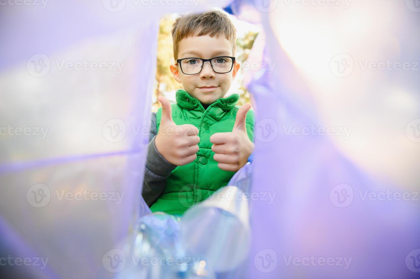 boy throws plastic trash in a bag in the park photo