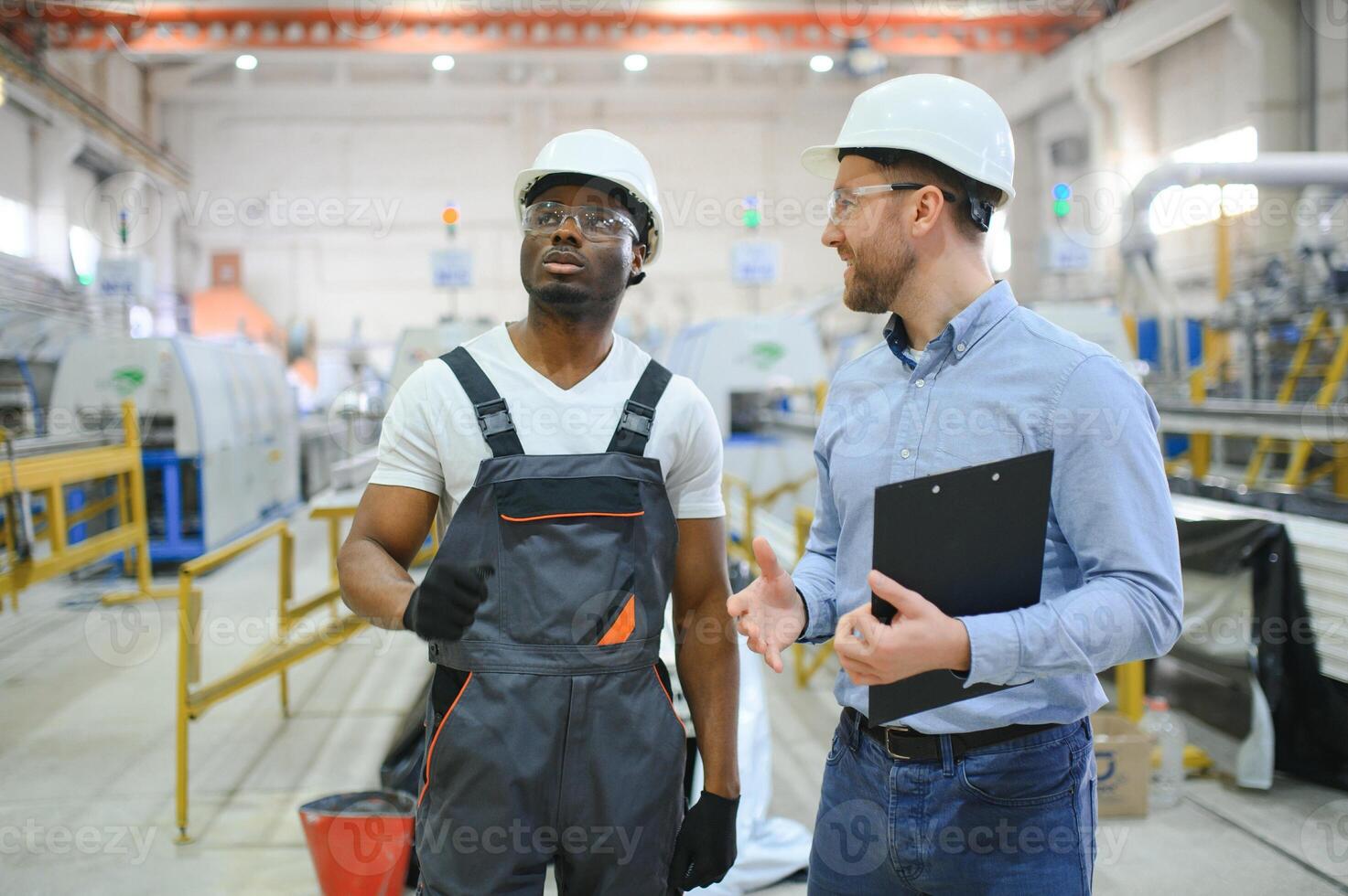 An engineer communicates with a worker on a production line photo