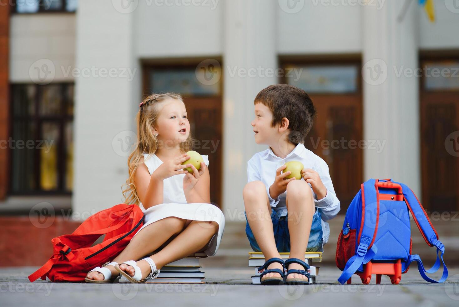 Happy children - boy and girl with books and backpacks on the first school day. Excited to be back to school after vacation. Full length outdoor portrait. photo