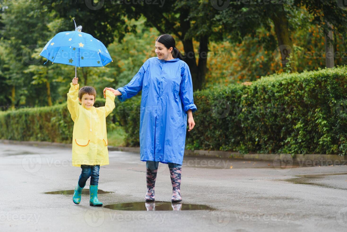 Mother with son walking in the rain under the umbrella photo