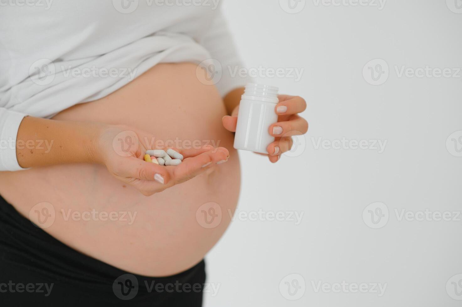 belly of pregnant woman and vitamin pills in the hand photo