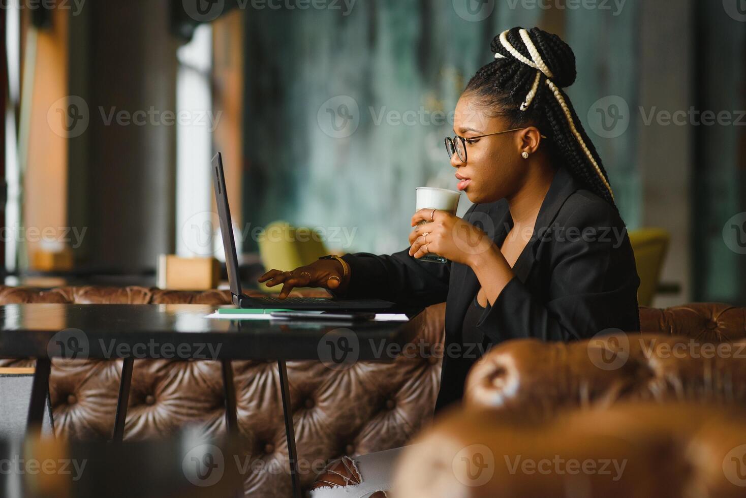 Portrait of a young black woman smiling and using laptop photo