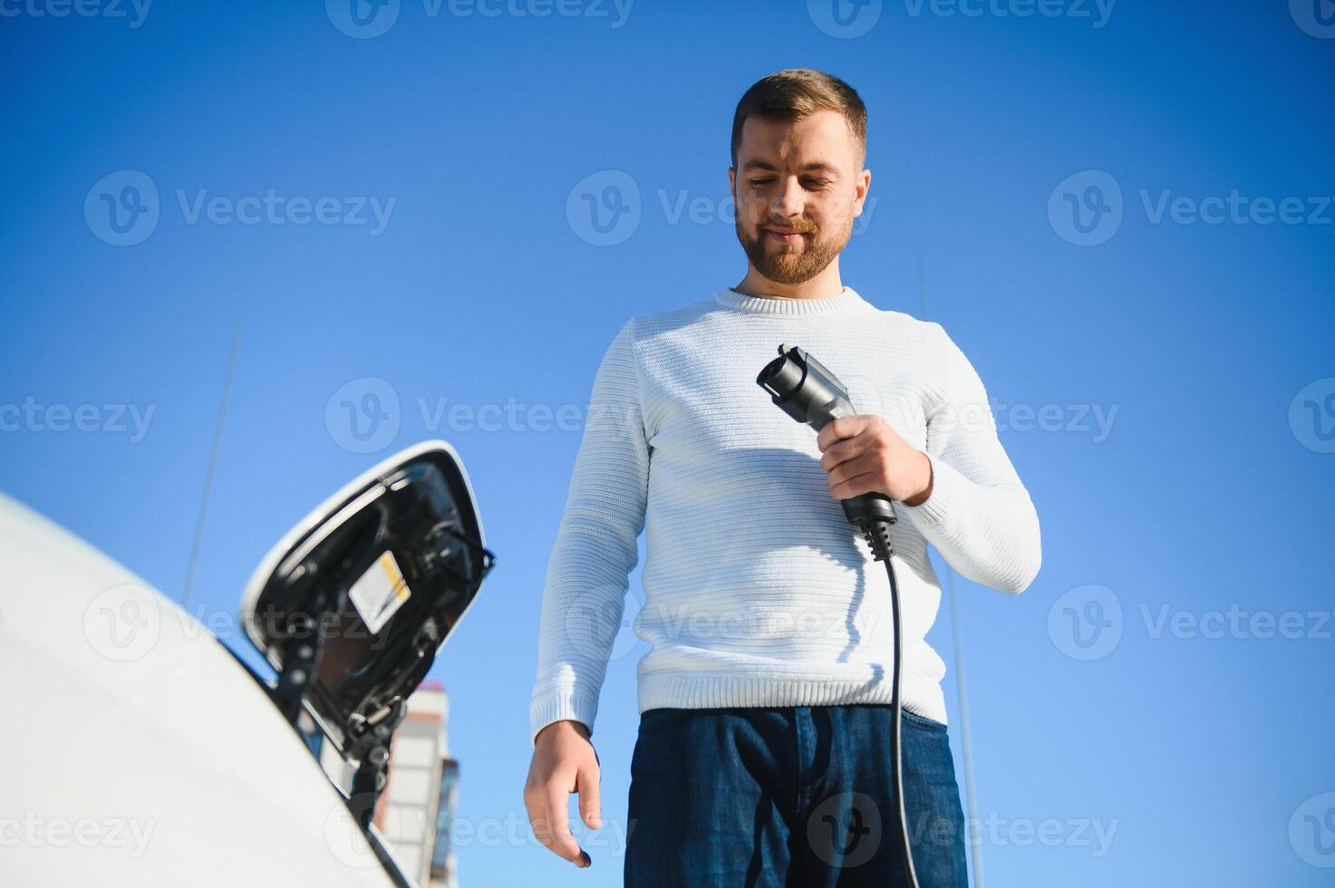 Man charges an electric car at the charging station photo