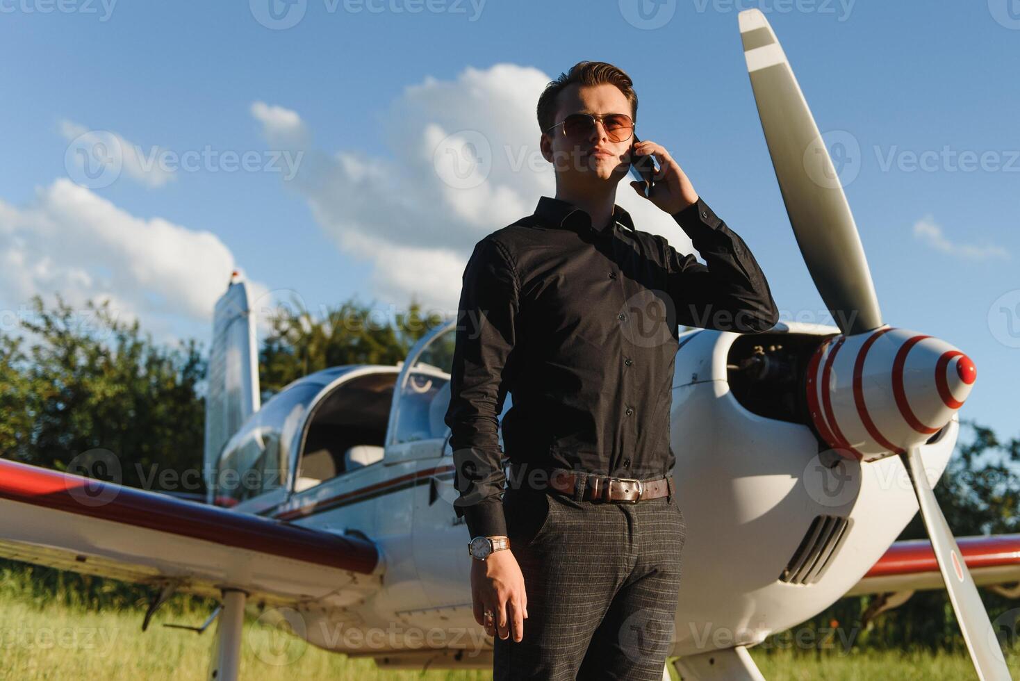 Young handsome businessman is standing near private plane. Confident and successful man in airport. photo