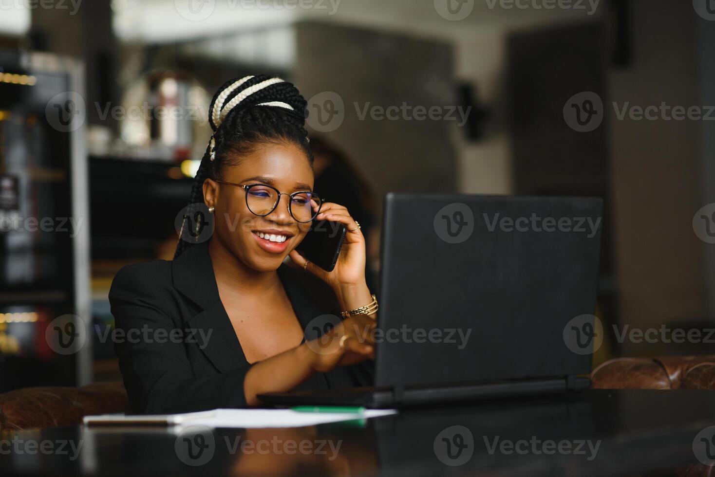 Young girl in glasses amazingly looking in laptop at cafe. African American girl sitting in restaurant with laptop and cup on table. Portrait of surprised lady with dark curly hair in earphones photo
