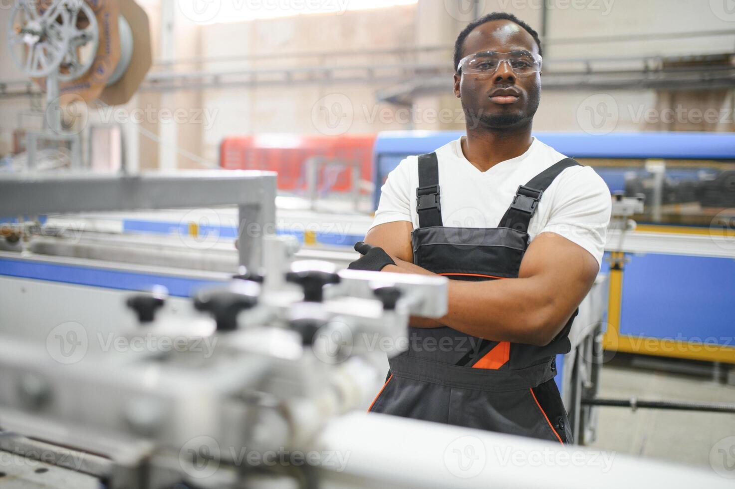 Portrait of African American male engineer in uniform and standing in industrial factory photo