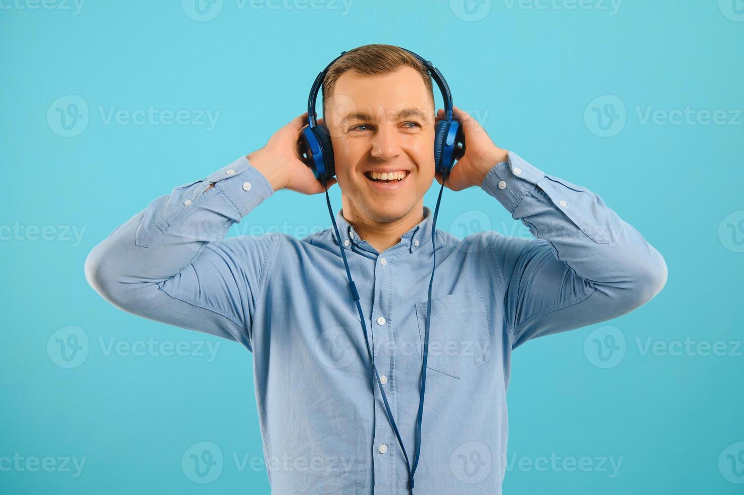 Handsome young man listening to music on color background photo