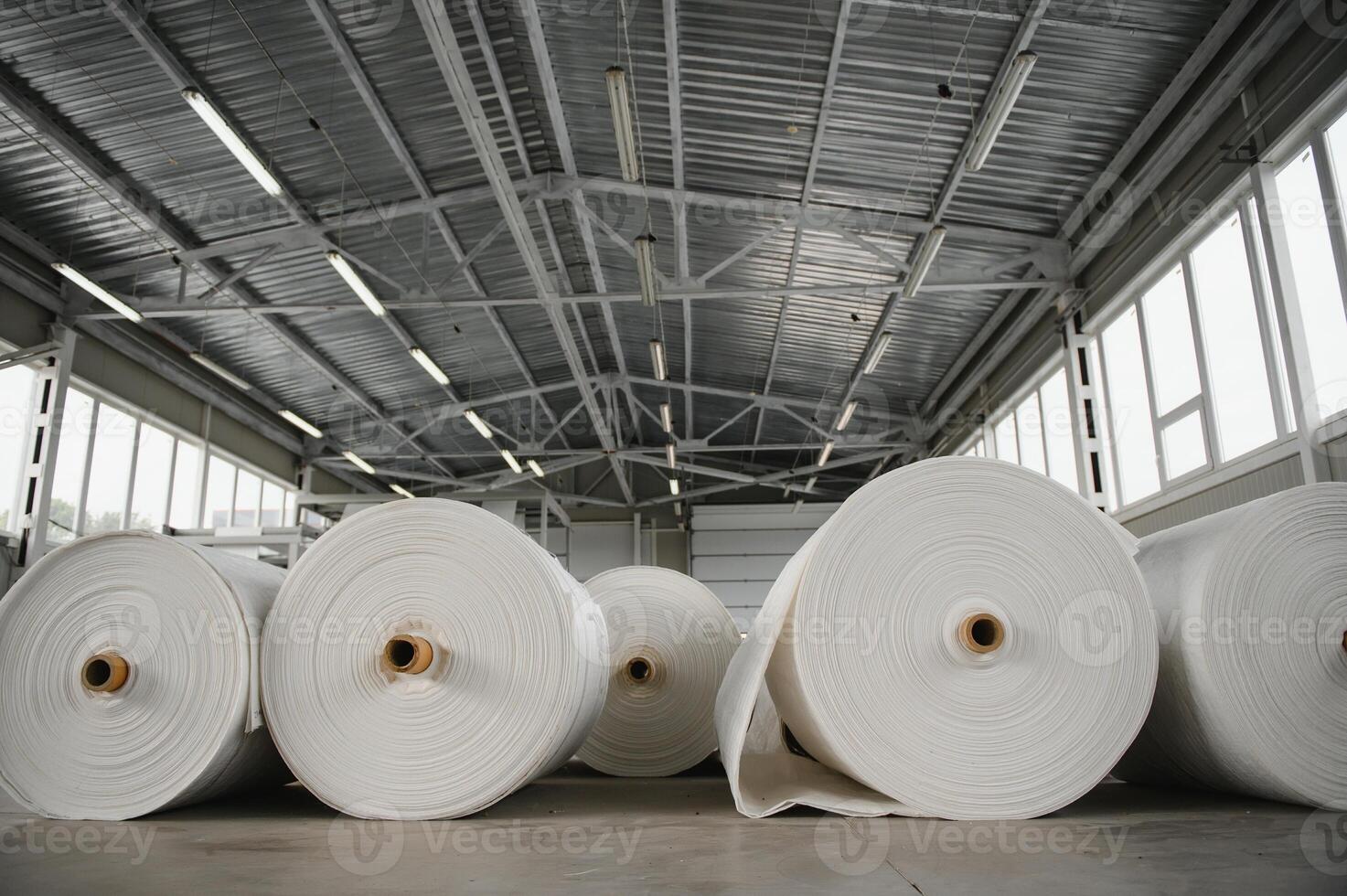 Raw materials warehouse. Many large coils of finished propylene hose made of woven thread for making industrial bags. Polypropylene rolls for packaging. photo