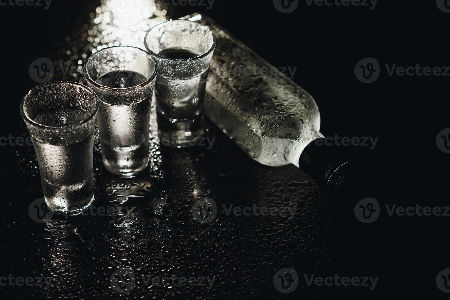 Cold vodka in shot glasses on a black background. Top view. Food background. photo