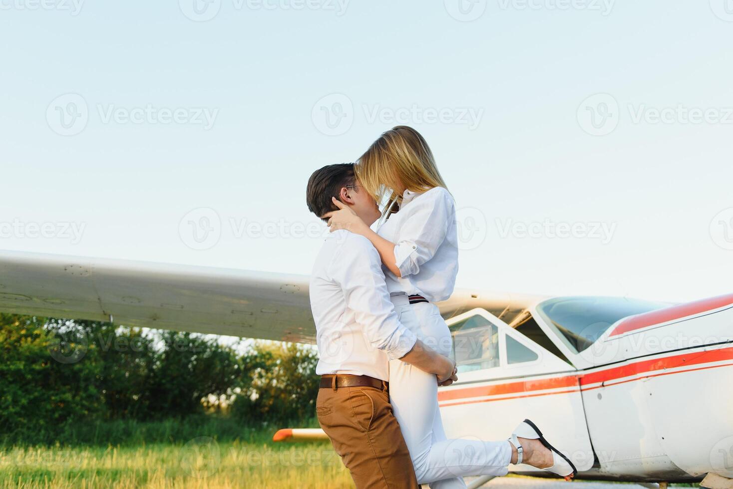 contento joven Pareja riendo y teniendo divertido en pista cerca privado aeronave foto