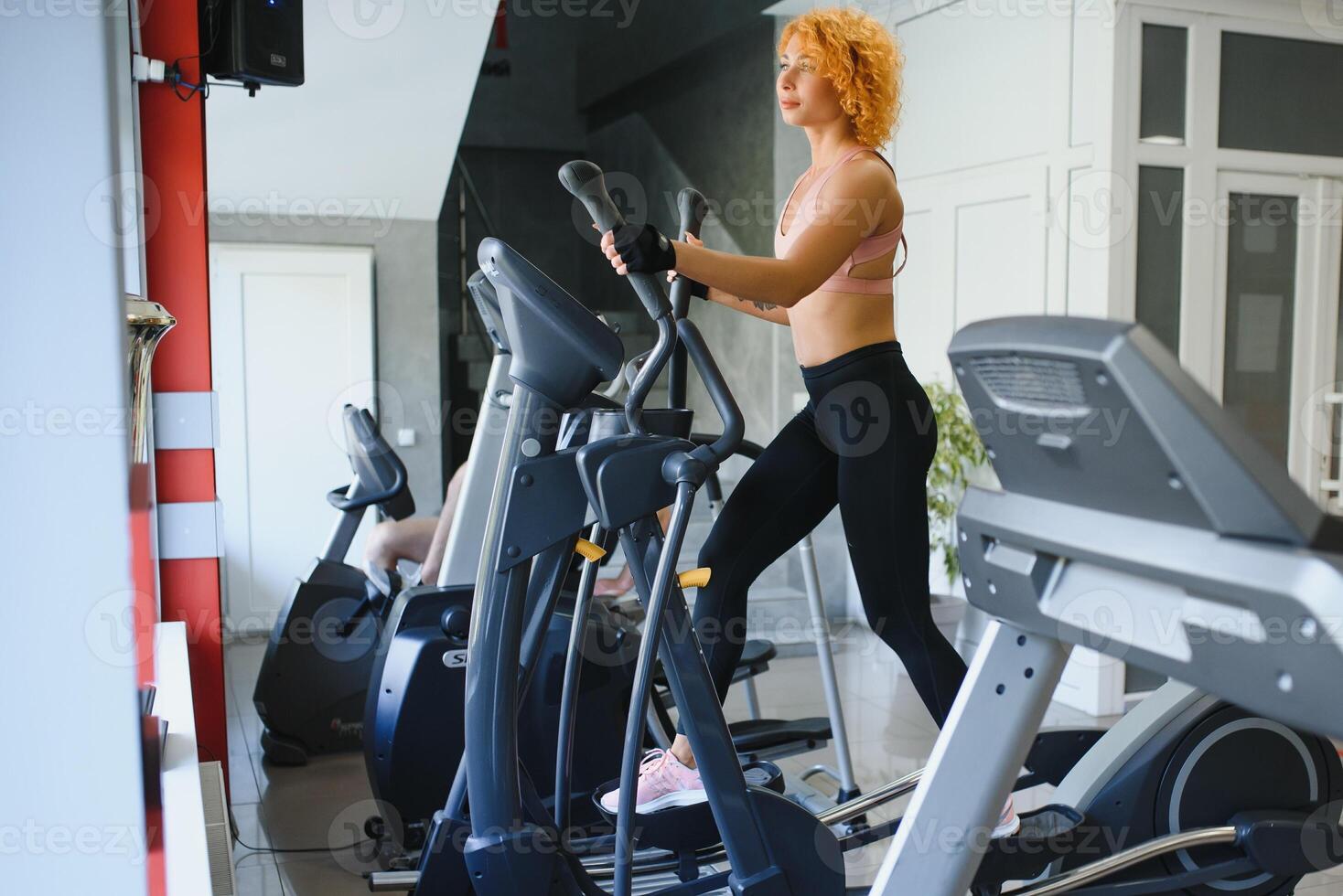 Attractive young sports woman is working out in gym. Doing cardio training on treadmill. Running on treadmill. photo