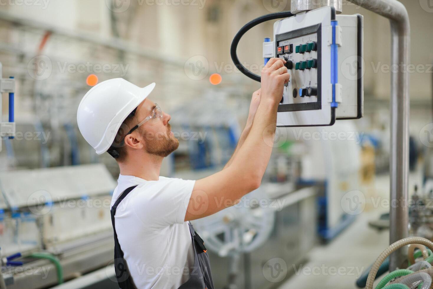 Smiling and happy employee. Industrial worker indoors in factory. Young technician with hard hat photo