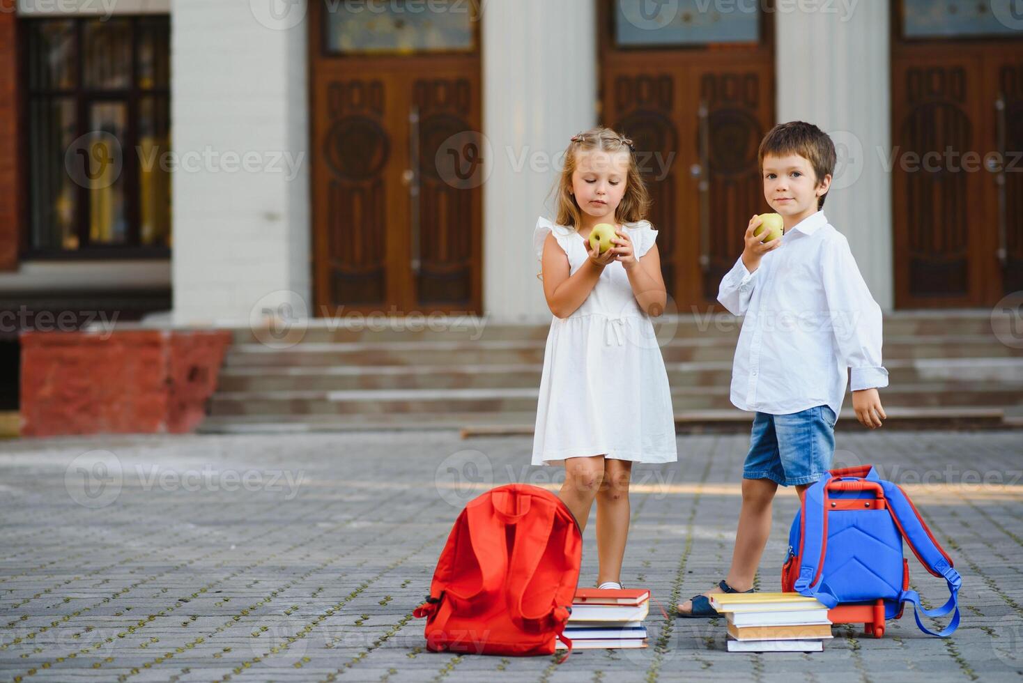 contento niños - chico y niña con libros y mochilas en el primero colegio día. emocionado a ser espalda a colegio después vacaciones. lleno longitud al aire libre retrato. foto