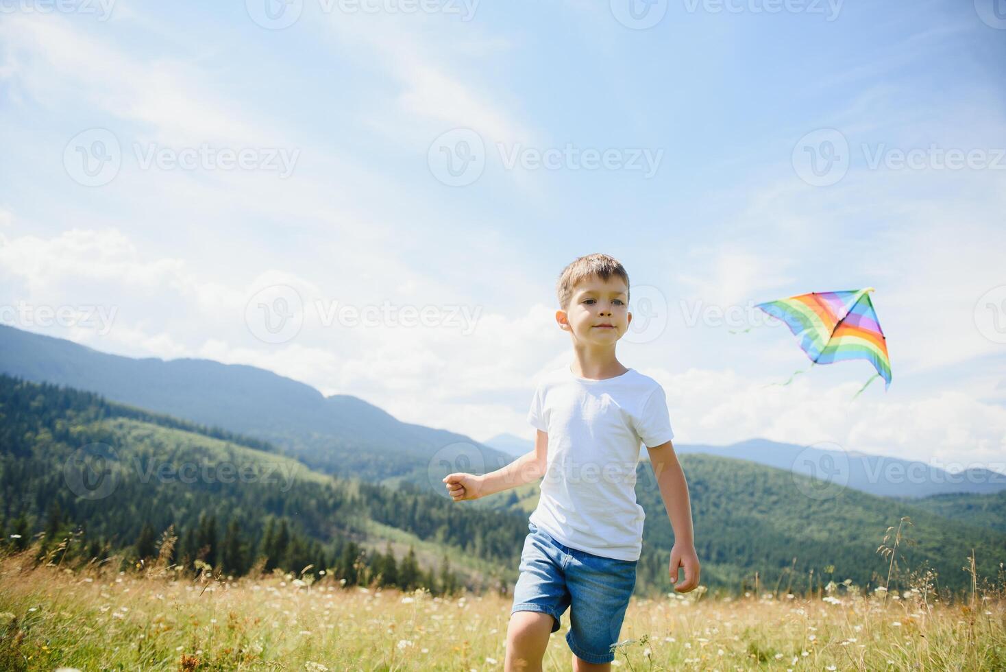 little boy holds string of kite flying in blue sky with clouds in summer with copyspace photo