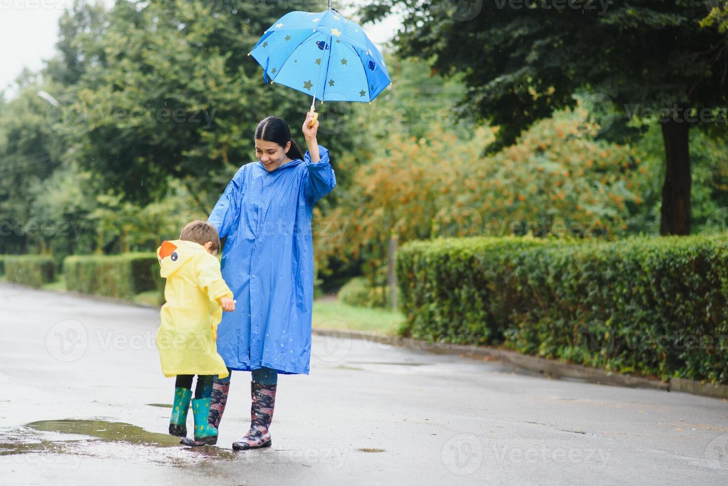Mother with son walking in the rain under the umbrella photo