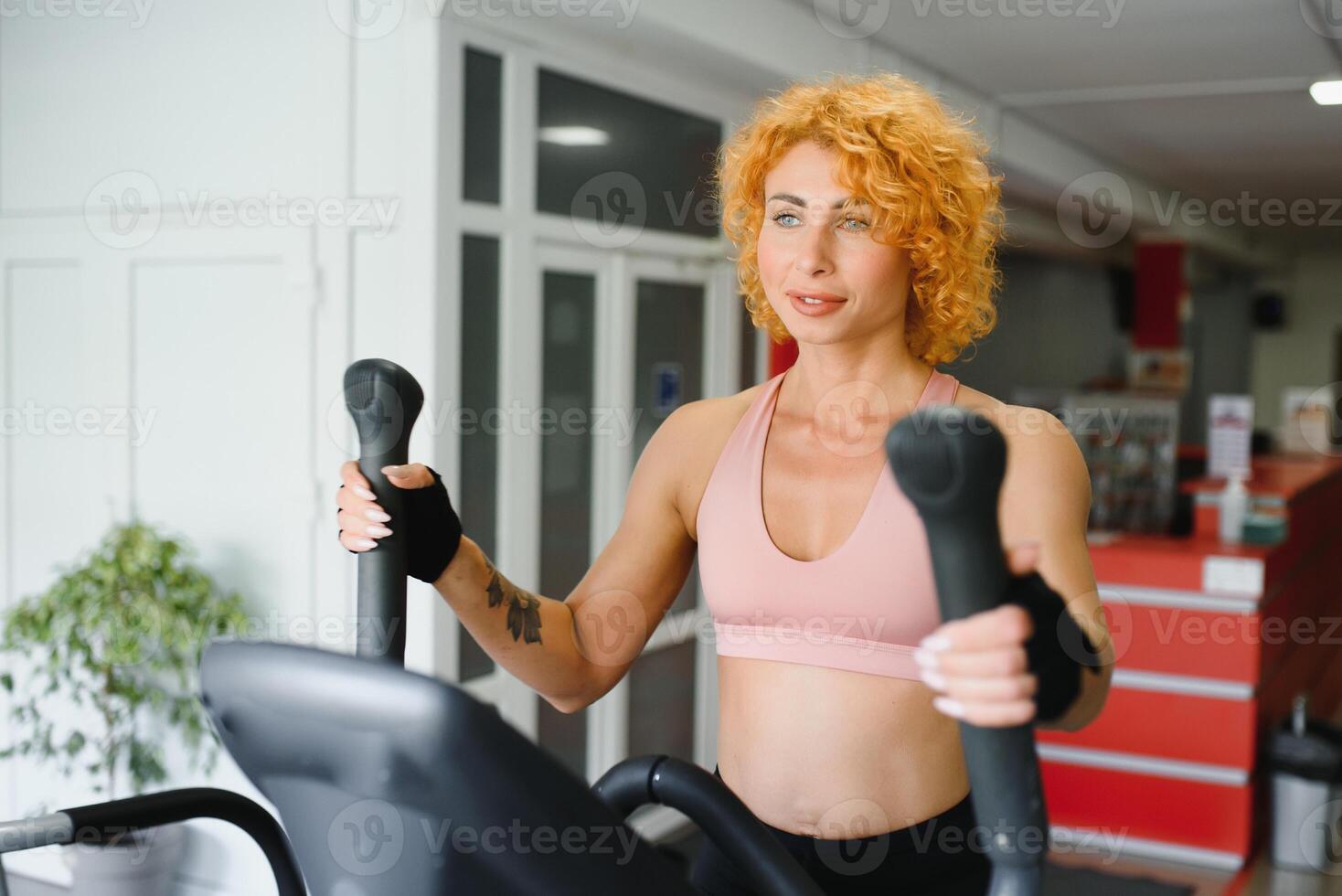Attractive young sports woman is working out in gym. Doing cardio training on treadmill. Running on treadmill. photo