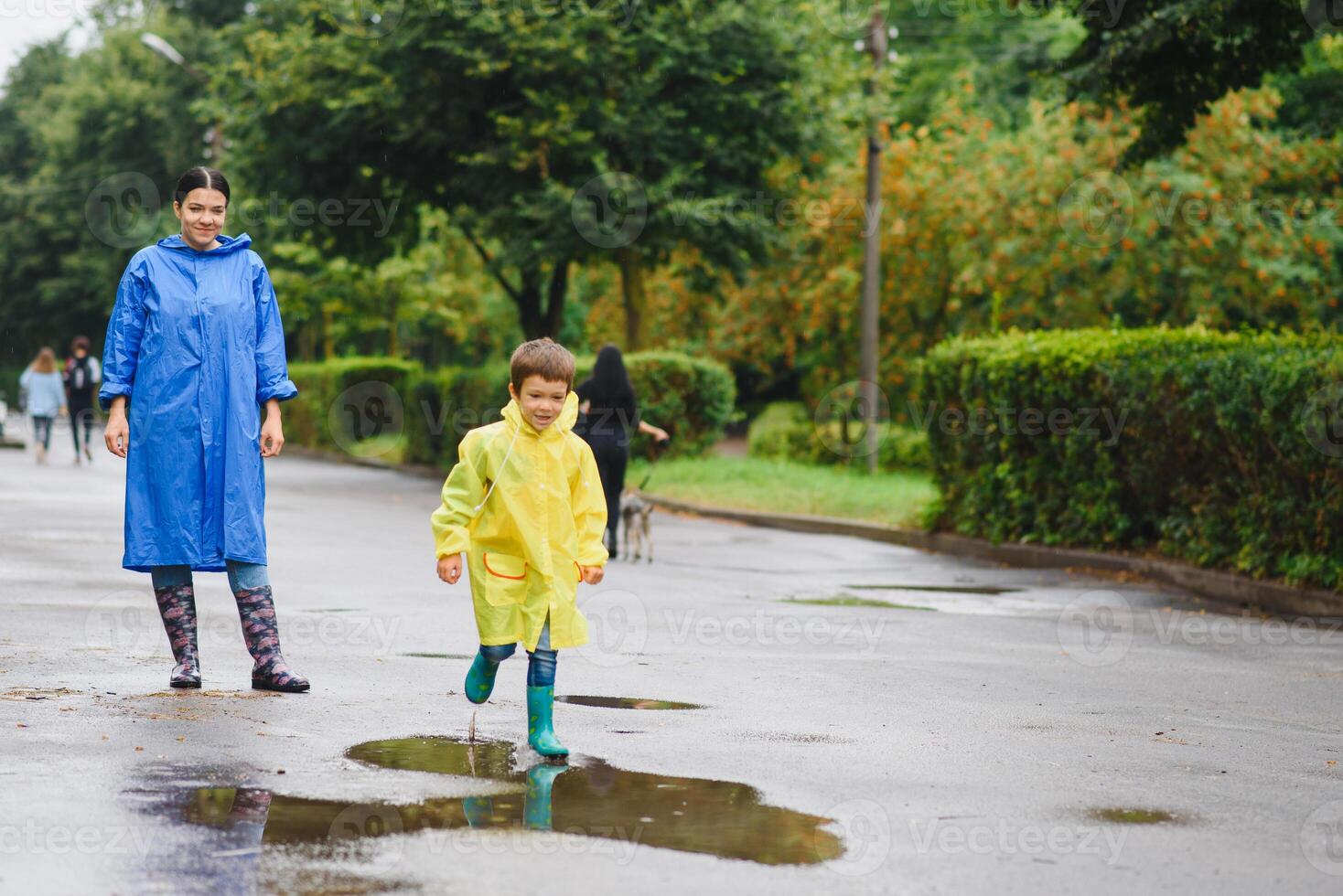 Mother and child, boy, playing in the rain, wearing boots and raincoats photo