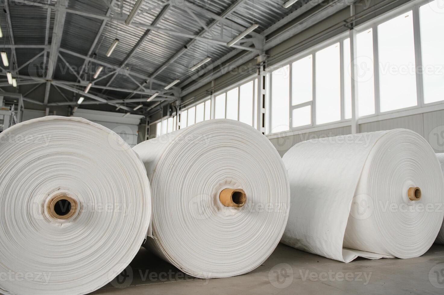 Raw materials warehouse. Many large coils of finished propylene hose made of woven thread for making industrial bags. Polypropylene rolls for packaging. photo