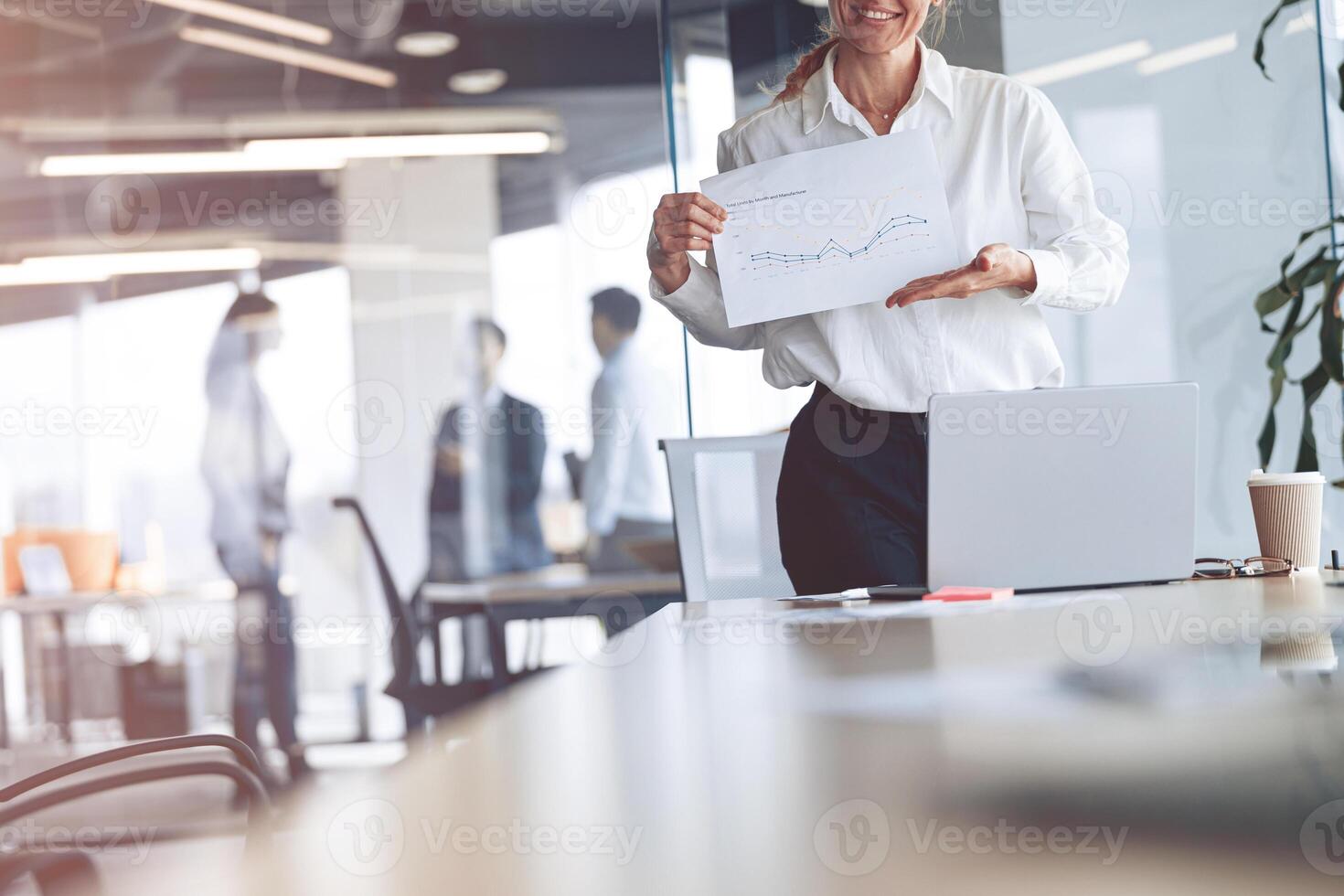 Positive mature caucasian woman, smiling face, showing her new plans in modern office photo