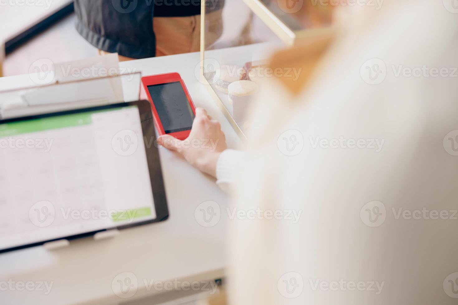 Close up of barista holds out a terminal for contactless paying to a client in coffee shop photo