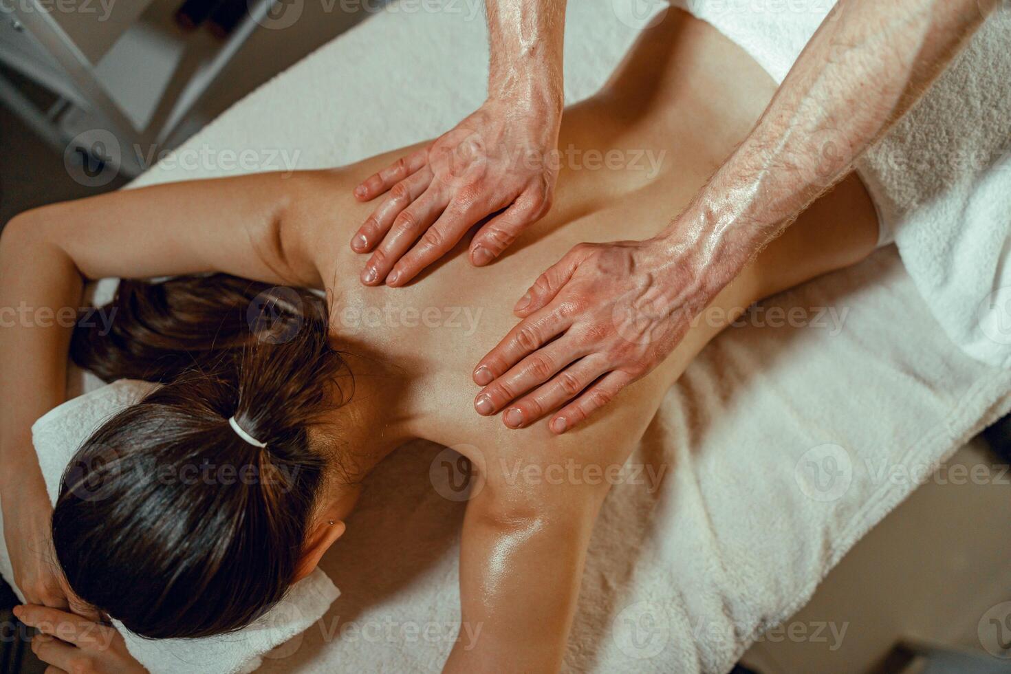 parte superior ver masajista hombre haciendo espalda masaje utilizando petróleo a un mujer en spa salón foto