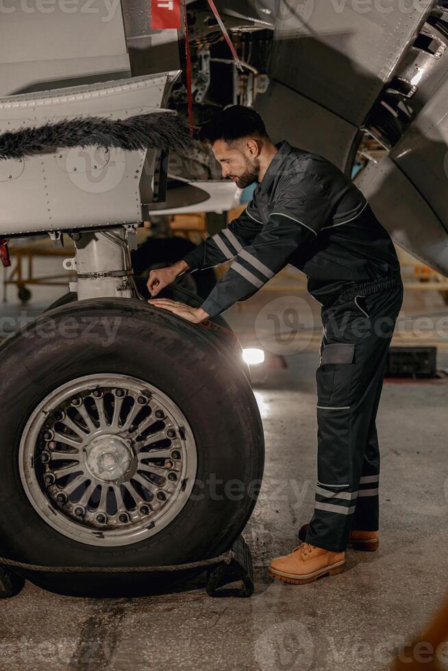 Male mechanic repairing airplane wheel in hangar photo