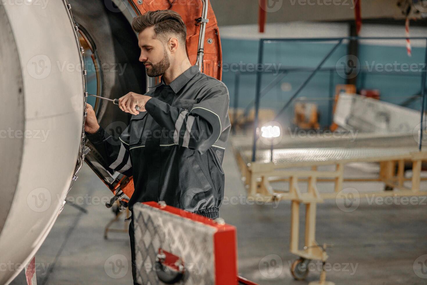 Male airline mechanic repairing aircraft in hangar photo