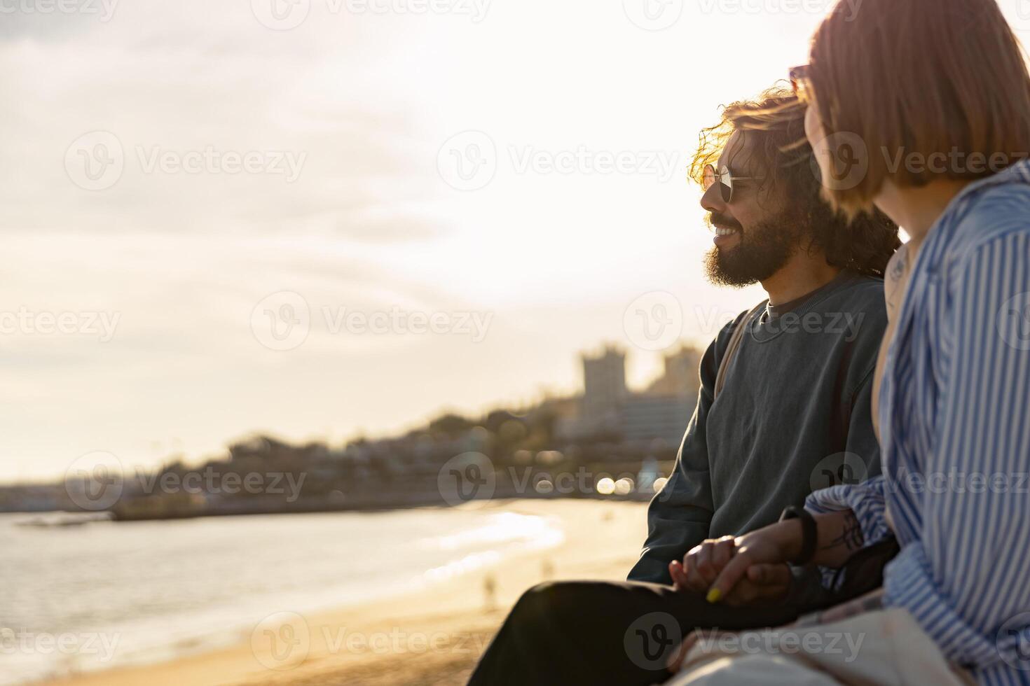 hermosa romántico Pareja sentado a el playa vistiendo casual ropa y mirando a el Oceano foto