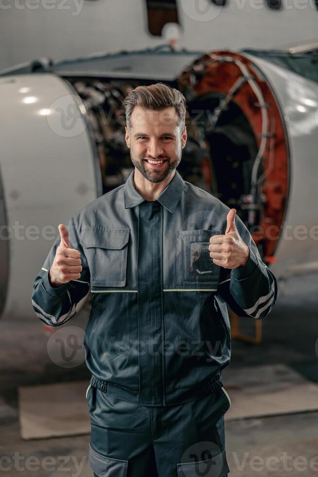 Cheerful airline mechanic showing approval gesture in hangar photo