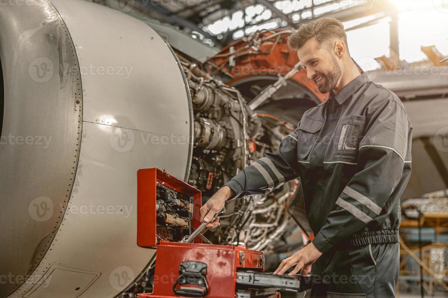 Joyful male mechanic using tool box in hangar photo