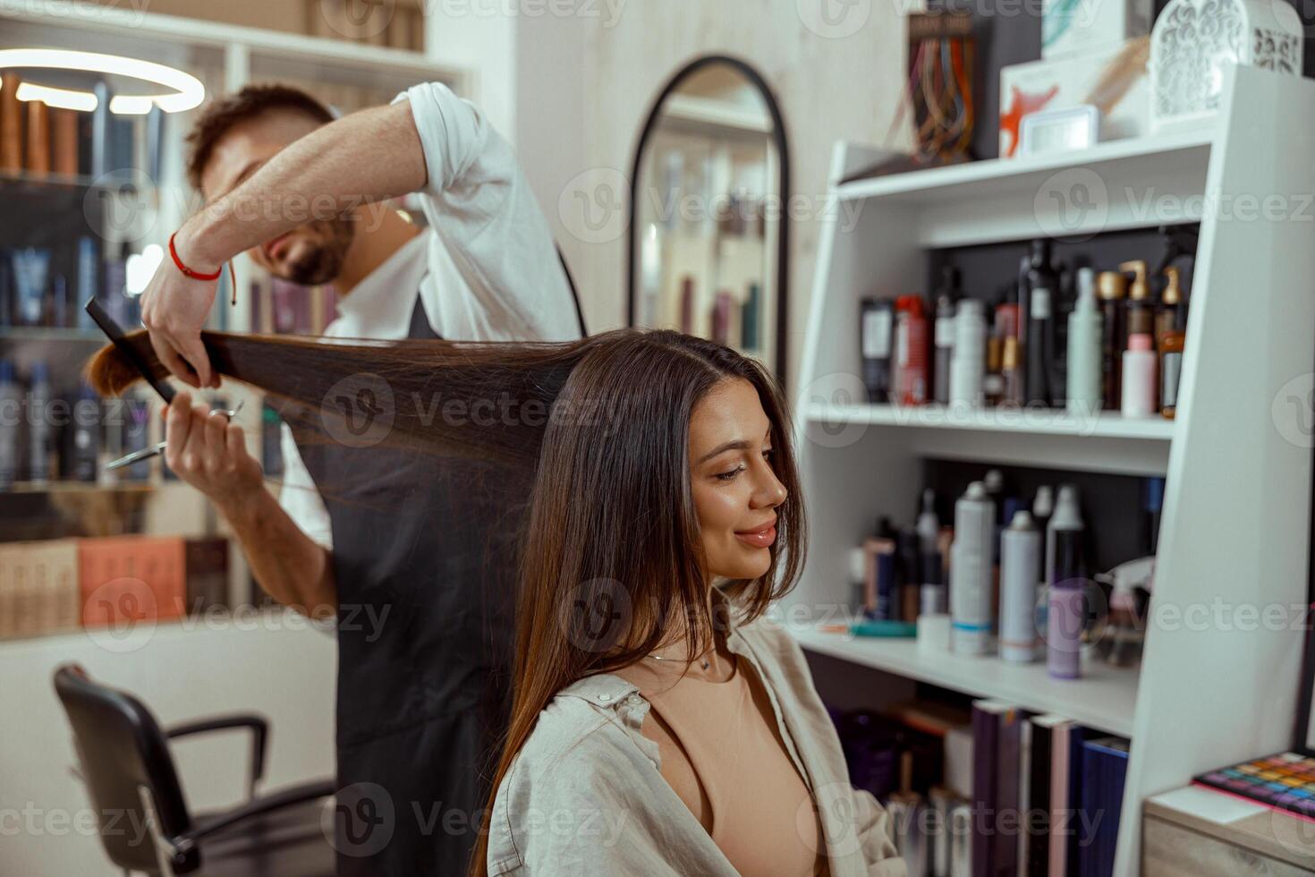 Professional hairdresser holding a comb while cutting hair of woman photo