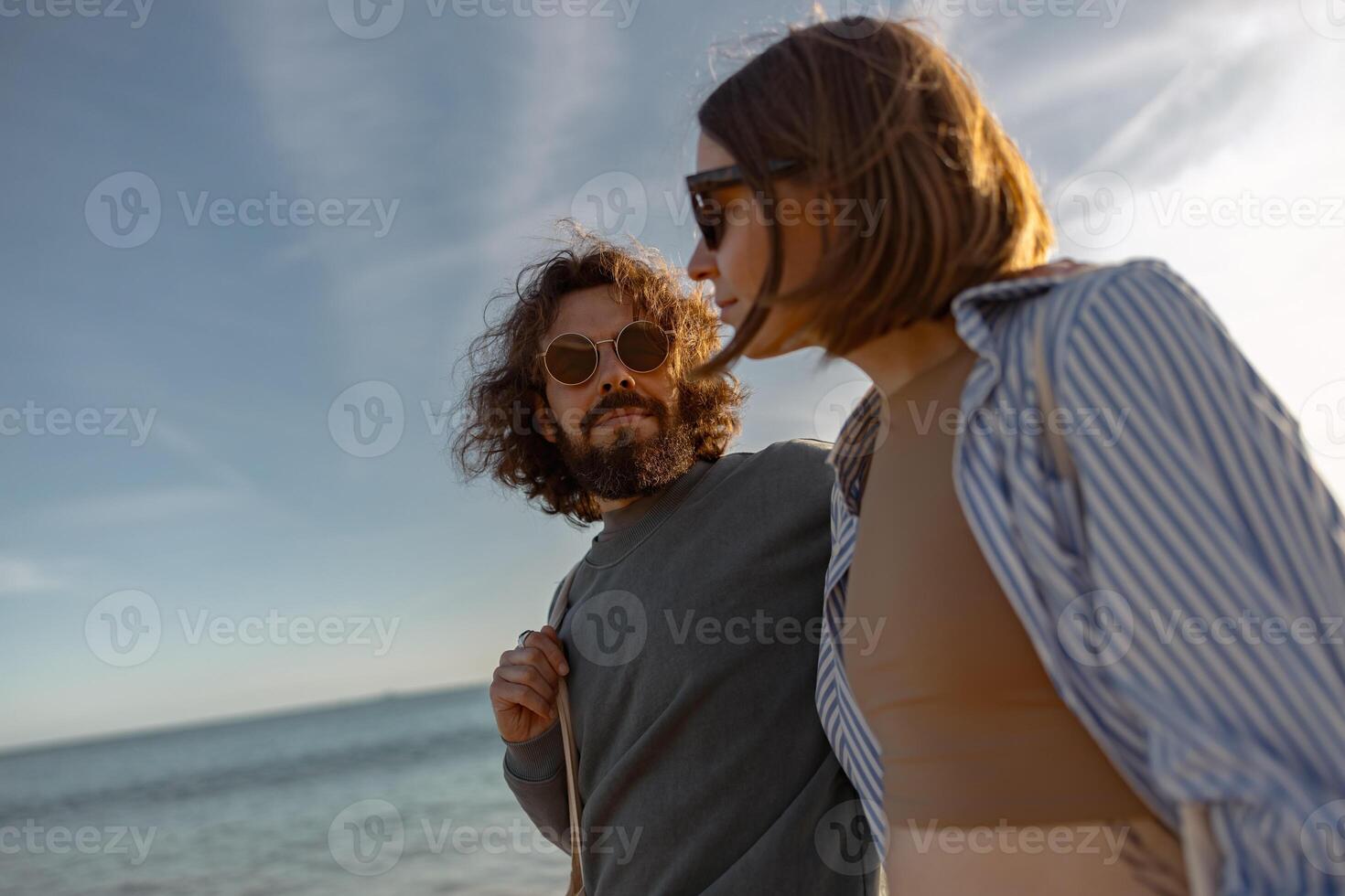 contento romántico Pareja en amor es caminar participación manos a través de el playa en puesta de sol foto