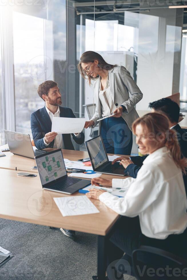Beautiful business people are using gadgets, talking and smiling during the conference in office photo