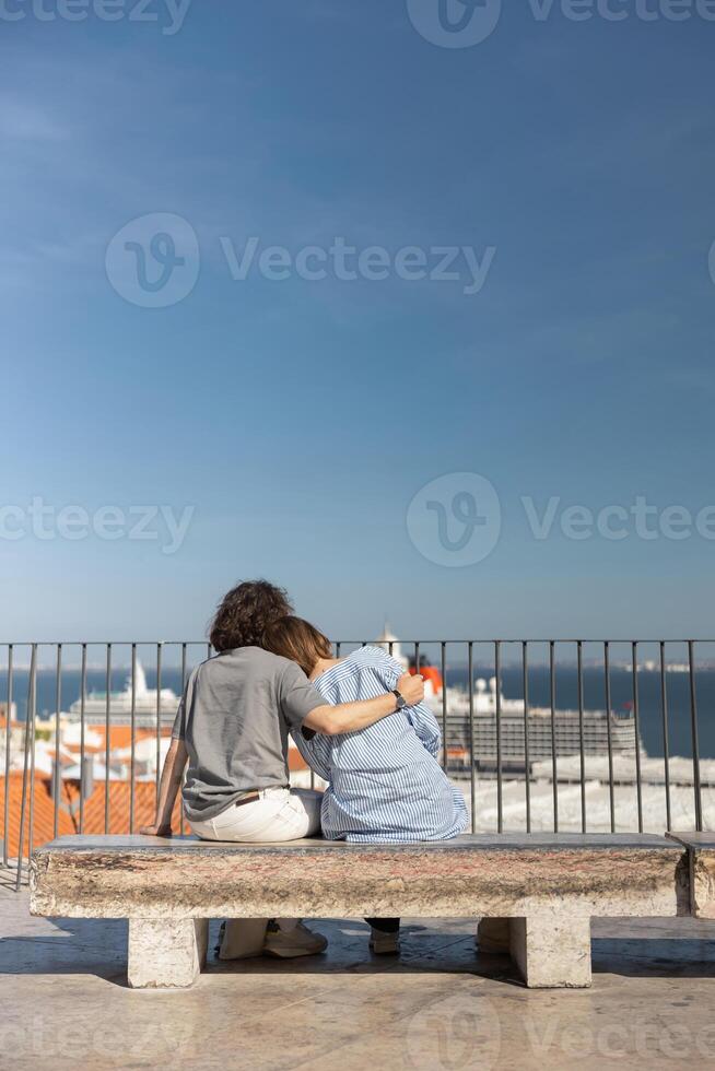 Back view of couple hugging while sitting on old city view with ancient architecture background photo