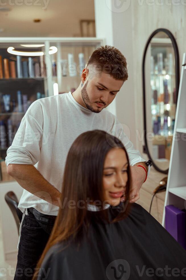 Young woman getting a haircut by professional male hairdresser at beauty salon photo