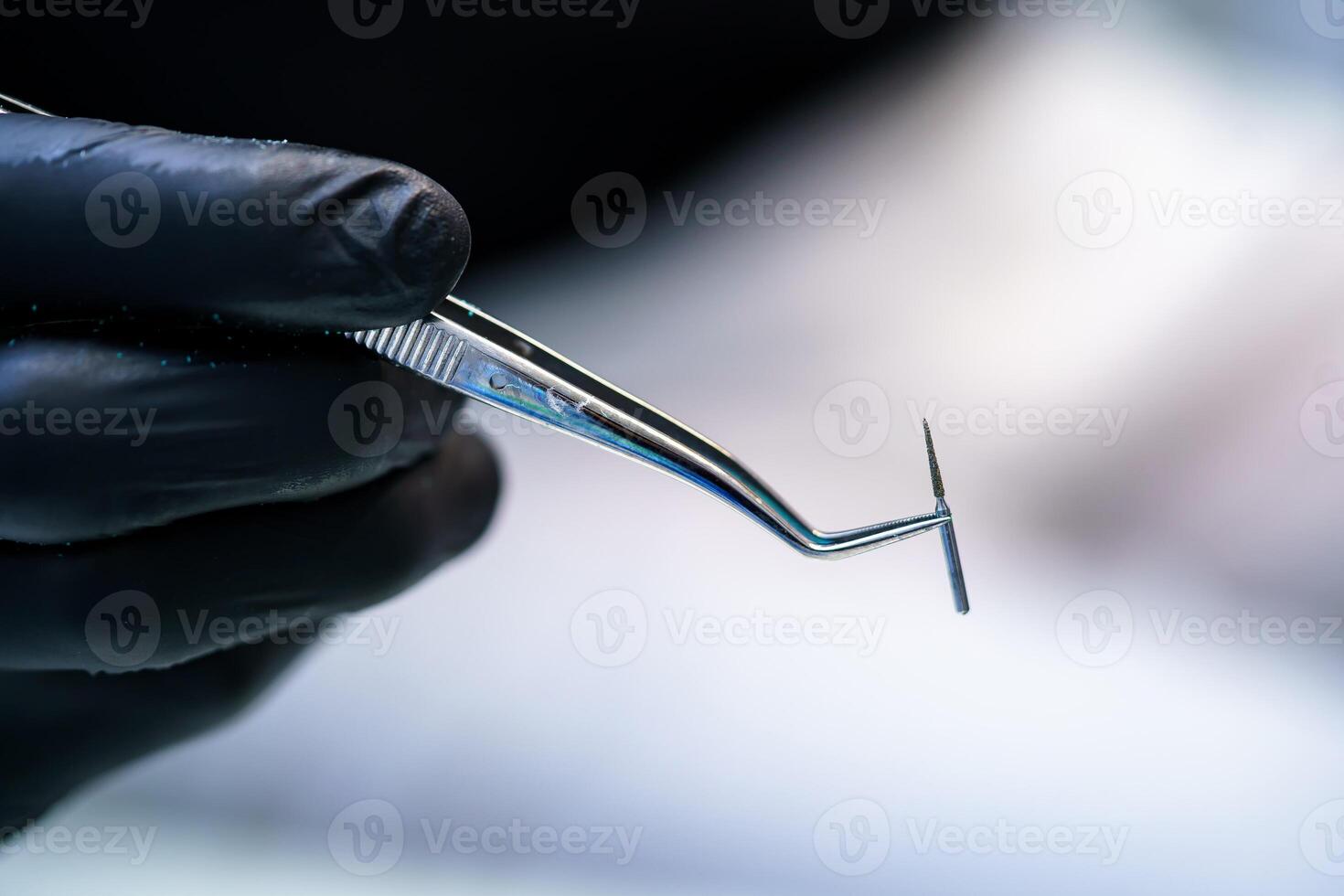Metallic head for dentist s drill. Dentist holds instruments in hands. photo