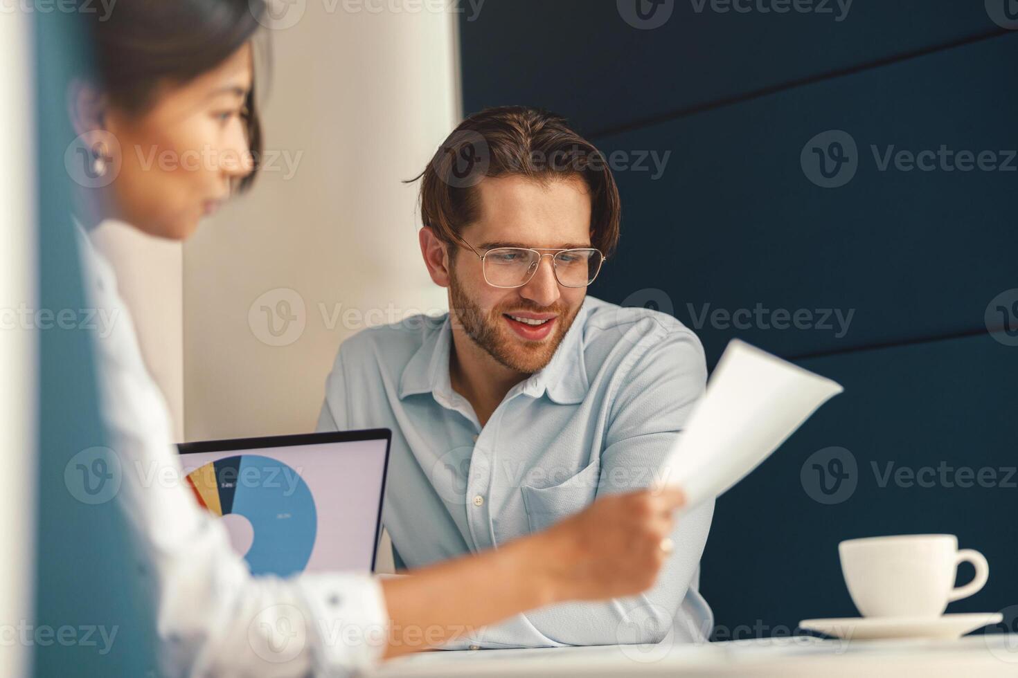 Two business colleagues working with documents together sitting in office. Teamwork concept photo