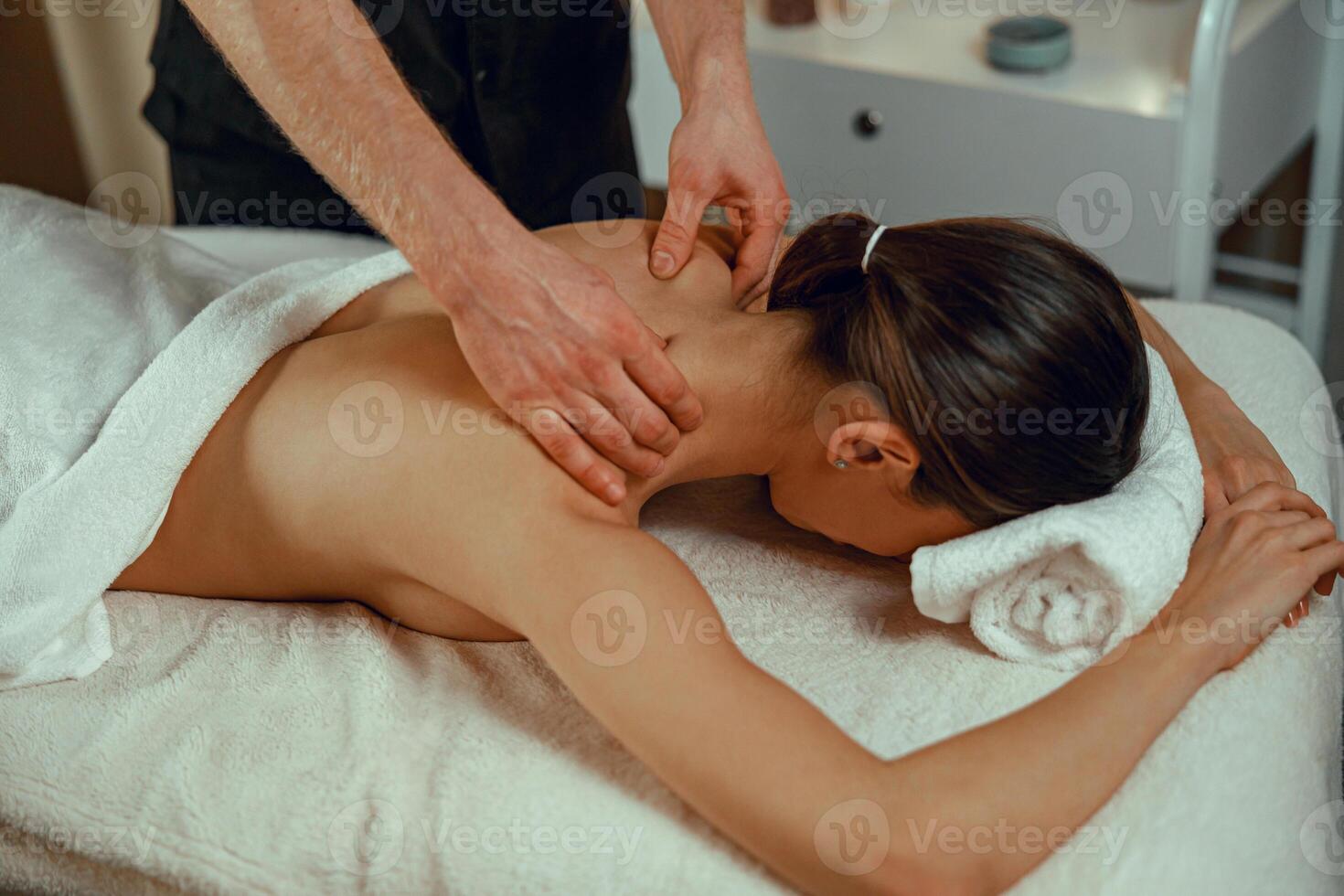 profesional masajista hombre haciendo espalda masaje para hembra cliente a spa centro. relajación, terapia foto