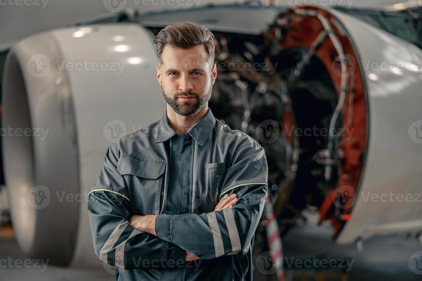 masculino aerolínea mecánico en pie cerca avión en hangar foto