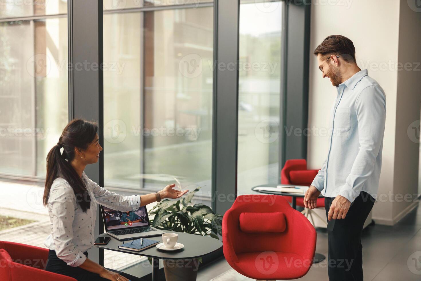 Female boss invites a colleague to sit down to conduct a video conference with the client together photo