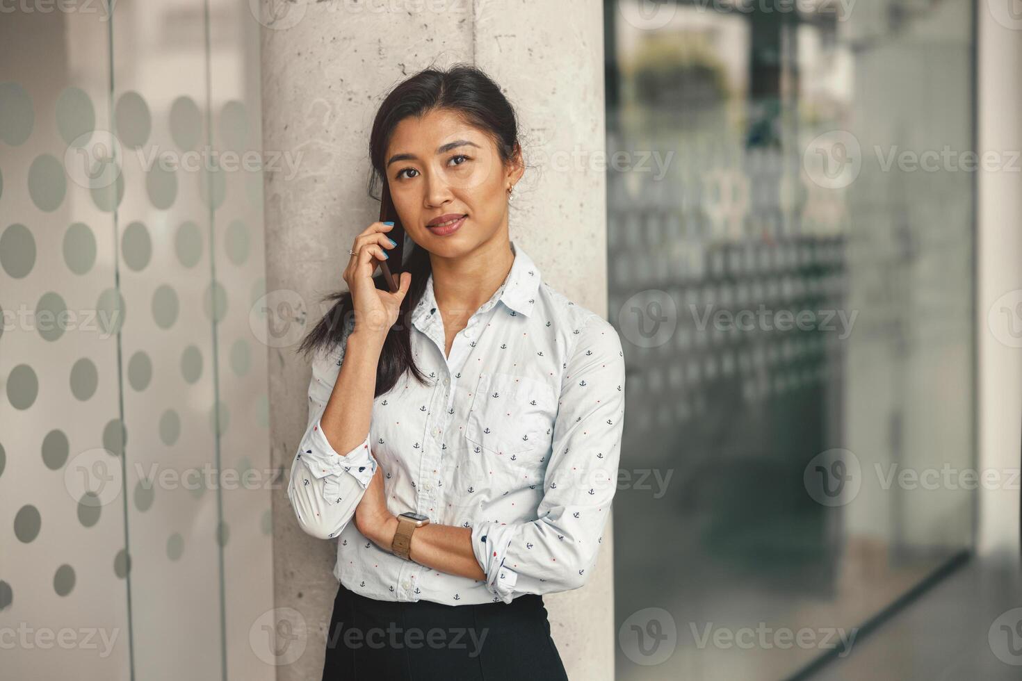 sonriente hembra persona de libre dedicación hablando teléfono con cliente mientras en pie en trabajo colaborativo y mirando cámara foto